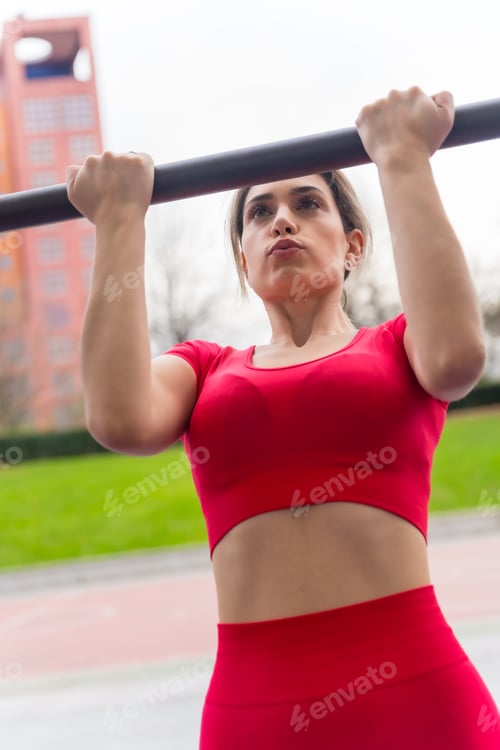 Preview: Fit woman in red outfit doing arm exercises in a park, fitness and healthy active concept