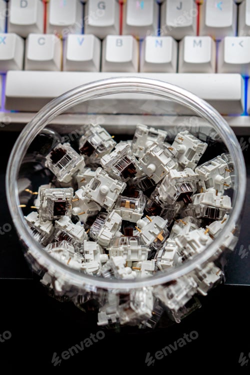 Preview: Vertical closeup of mechanical keyboard switches piled in a transparent jar