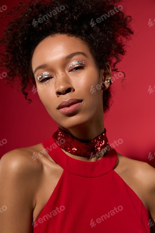 Preview: Beautiful portrait of a young woman with sparkling makeup against a vibrant red background