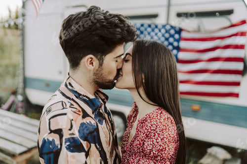 Preview: Beautiful Spanish couple kissing on background of the US flag - US Independence day
