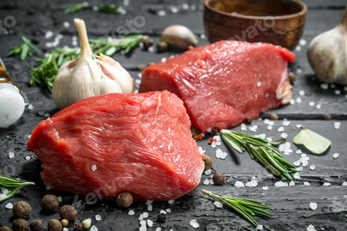 Preview: Raw meat. Sliced pieces of beef with spices and herbs on a wooden Board.