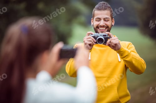Preview: Happy couple taking photos of each other in the countryside