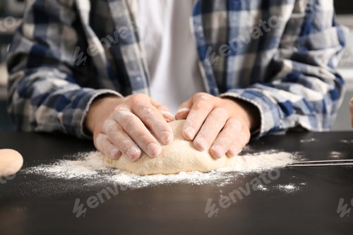 Preview: Man kneading dough on table covered with flour in kitchen