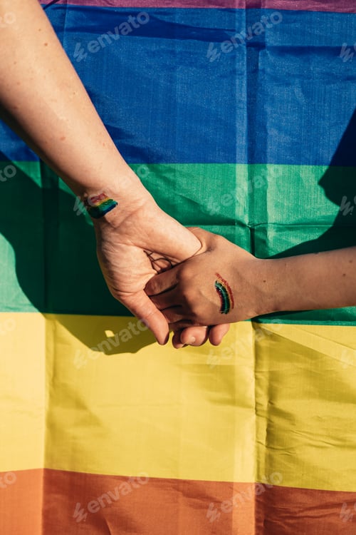 Preview: A mother holding hands with her daughter in the background the gay pride flag, lgtb concept