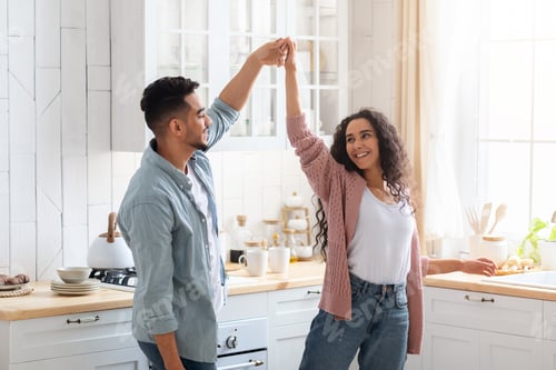 Preview: Happy Middle Eastern Couple Dancing Together In Kitchen, Having Fun At Home