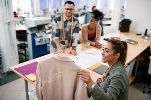 Preview: Happy fashion designers working on new clothing line in a design studio.