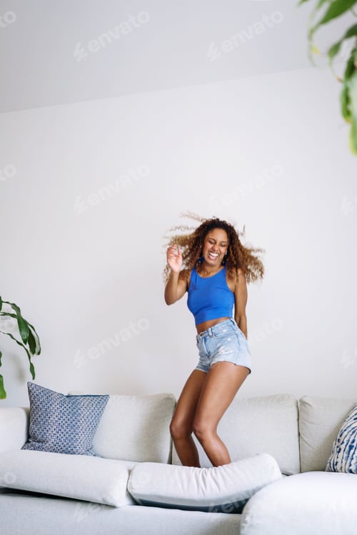 Preview: Young Black woman standing on the couch dancing and having fun