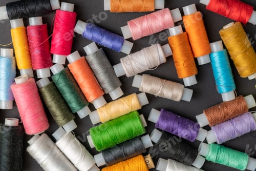 Preview: bunch of colorful sew threads lay on dark background isolated d