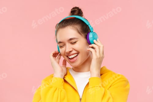 Preview: Young smiling teen girl enjoying favorite music through wireless headphones with closed eyes