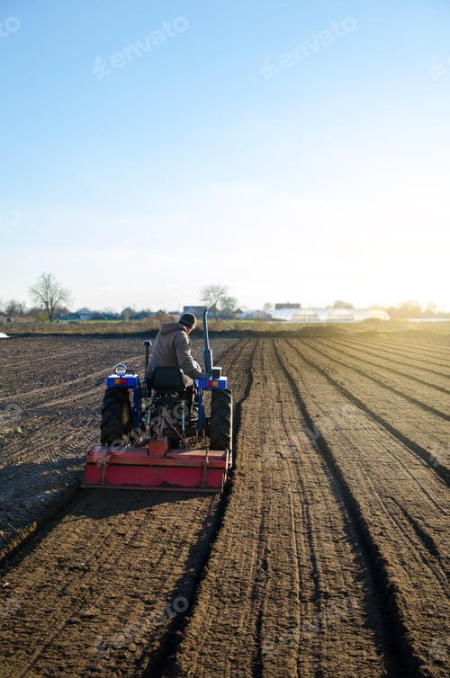 Preview: The tractor is cultivating the soil in the farm field.