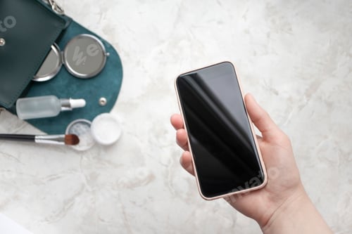 Preview: Hand holding smartphone on beauty makeup products