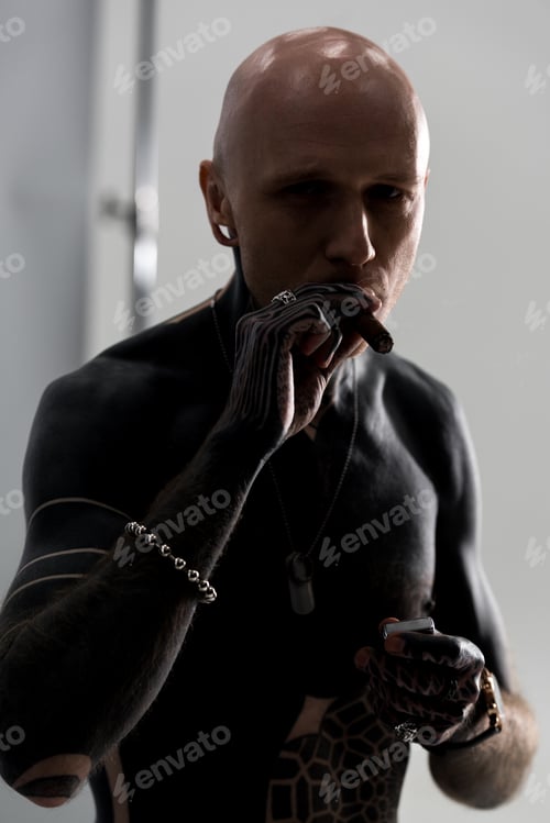 Preview: handsome shirtless man with tattoos smoking cigar and looking at camera