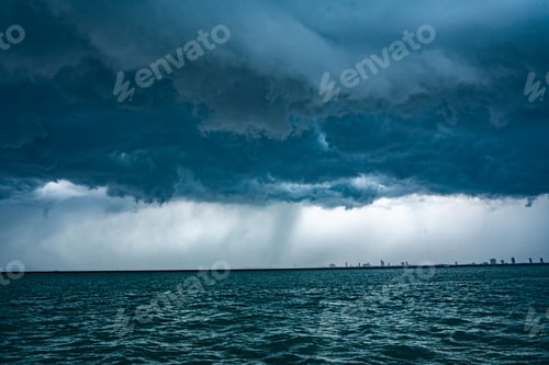 Preview: Tropical ocean storm menacing clouds and rain showering below, Light in the dark and dramatic storm