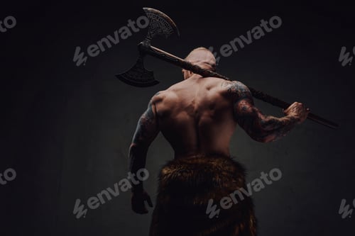 Preview: Rear view of healthy tattoed warrior in fur with axe on a dark background