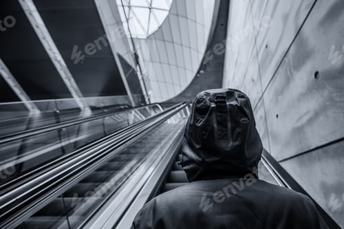 Preview: Unrecognizable hooded person on moving escalator