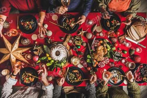 Preview: Flat-lay of friends eating and talking at festive Christmas table