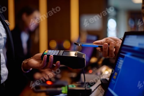 Preview: Close up of man using smart phone while paying in a hotel.