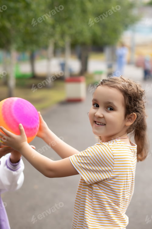 Preview: Portrait of happy kid girl child in park with colorful rainbow ball