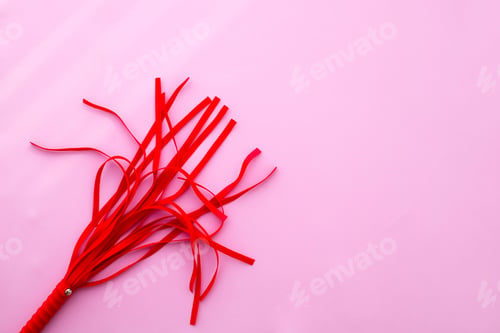 Preview: Leather red whip on a pink background. Sex toy.