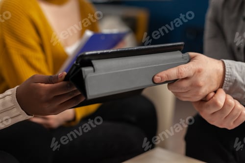Preview: Happy multiethnic group of business people looking at tablet briefing ideas