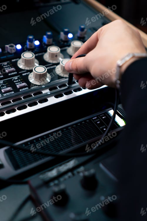 Preview: close up in dark recording studio the sound engineer works with the remote control and connects the