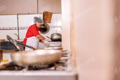 Preview: Woman cooking fried food in small restaurant kitchen