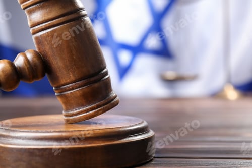 Preview: Judge's gavel on wooden table against flag of Israel, closeup. Space for text
