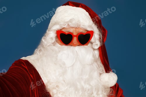 Preview: Authentic Santa Claus in sunglasses taking selfie on blue background