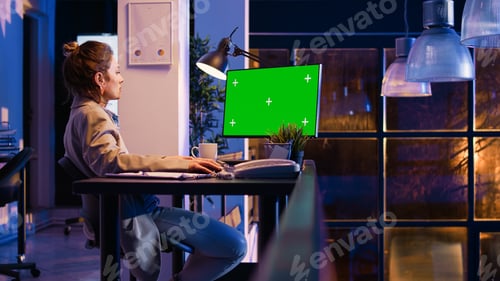Preview: Young entrepreneur using pc with green screen at night