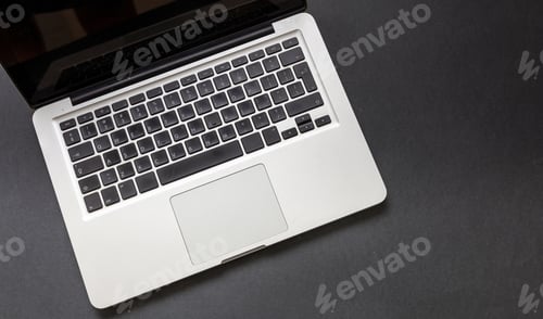Preview: Laptop computer on black color background. Open laptop keyboard metal silver top view.