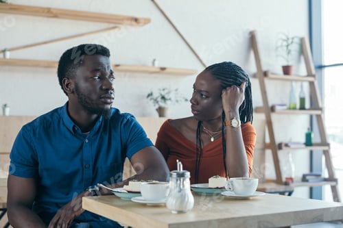Preview: insulted african american man sitting at table with girlfriend in cafe