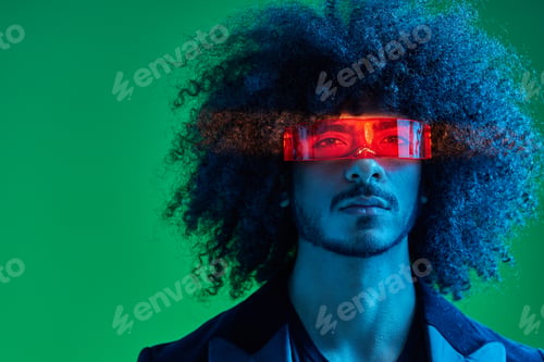 Preview: Portrait of a fashion man with curly hair on a green background wearing red sunglasses