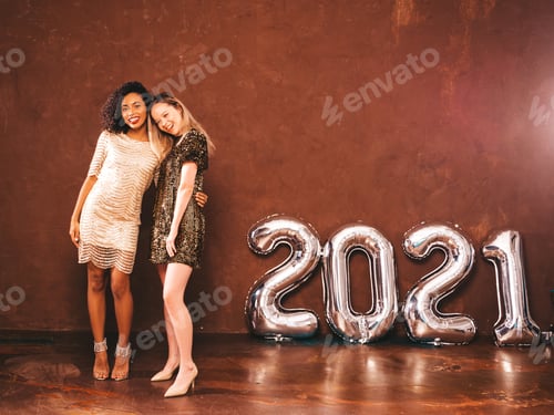 Preview: Portrait of two young stylish women posing in studio near wall