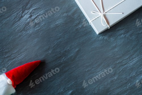 Preview: Top view of the Santa Claus toy with a white beard near a gift box - the concept of New Year
