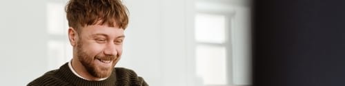 Preview: Young ginger man working with laptop while sitting at table in office