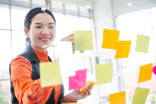 Preview: Asian woman working on post paper and stick on glass wall
