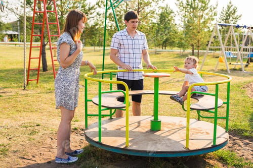 Preview: young mother and father playing with their baby on the playground