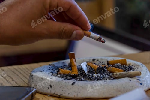 Preview: Closeup shot of a young man smoking on a wooden table