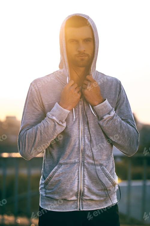 Preview: Used to win. Handsome young man adjusting his hood and looking at camera while standing outdoors