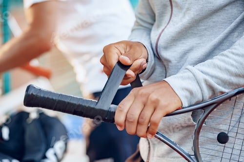 Preview: Unrecognizable tennis player repairs coverage of handle of tennis racket