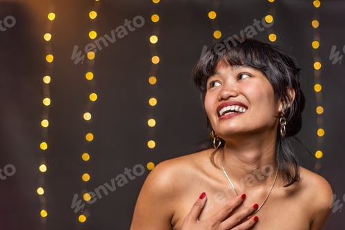 Preview: Portrait of an asian young woman smiling and looking away with a blurred light background with copy