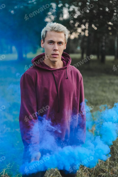 Preview: Street style man in hoodie hold hand flare with red smoke grenade bomb.