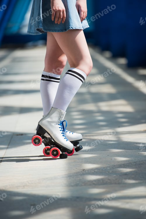 Preview: cropped shot of girl in denim skirt and vintage roller skates on street