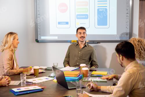 Vista previa: Grupo de empresarios sentados en una sala de reuniones discutiendo el diseño de una aplicación para teléfonos inteligentes.