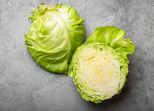 Preview: Fresh raw organic farm cabbage cut in half on grey rustic stone background top view, healthy cabbage