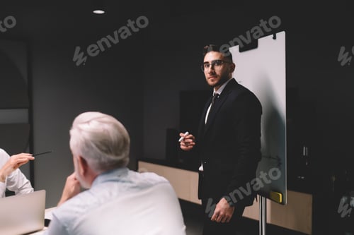 Visualização: Funcionário do sexo masculino explicando a estratégia de negócios para colegas de trabalho durante a conferência