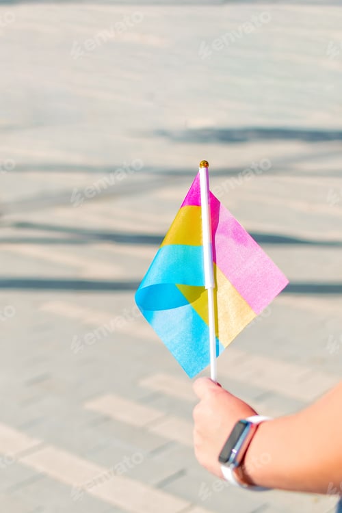 Preview: Female hand holding small lgbt pan sexual flag. LGBT pride flag.