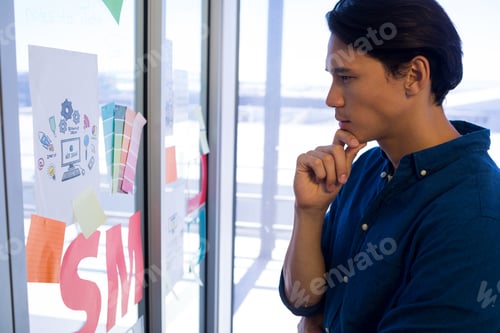 Preview: Male executive reading sticky notes on glass door