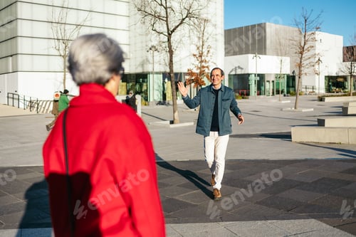 Preview: Senior friends warmly embracing, meeting on city sidewalk