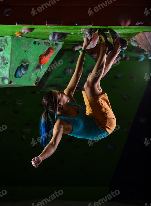 Preview: Young woman bouldering on ceiling in climbing gym